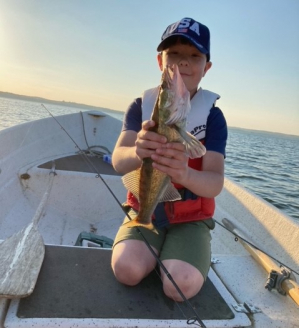 Poika pitelee veneessä kalaa